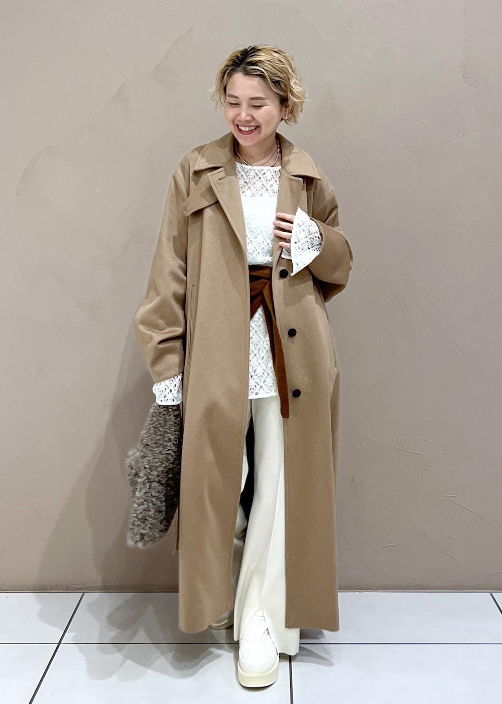 ブラウン系のハンドバッグ、ホワイト系のTシャツ/カットソー、イエロー系のステンカラーコートを着用したレディースの冬コーディネートの7枚目の写真