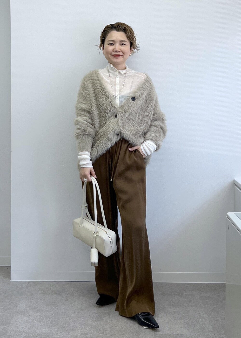 ベージュ系のカーディガン/ボレロ、ブラウン系のその他パンツ、ホワイト系のショルダーバッグを着用したレディースの秋コーディネートの2枚目の写真