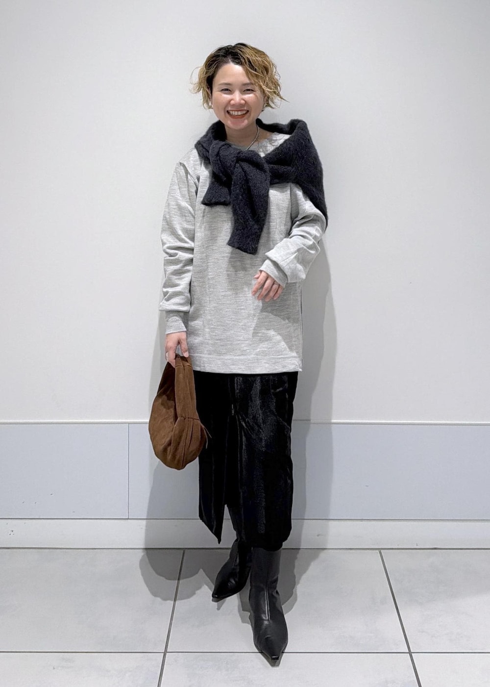 ブラック系のスカート、ブラウン系のハンドバッグ、ブラック系のブーツを着用したレディースの秋コーディネートの2枚目の写真