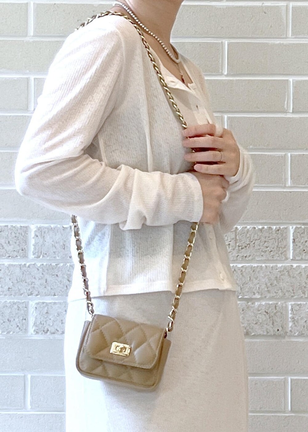 ホワイト系のスカート、ベージュ系のショルダーバッグ、ホワイト系のカーディガン/ボレロを着用したレディースの夏コーディネートの7枚目の写真