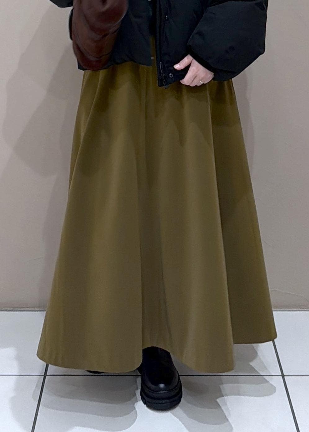 ブラウン系のスカート、ブラック系のダウンジャケット/コート、グレー系のニット/セーターを着用したレディースの冬コーディネートの9枚目の写真