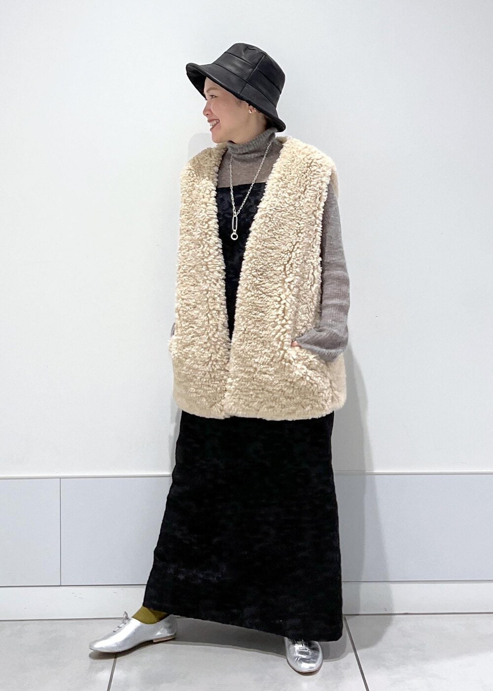 ベージュ系のベスト、ブラック系のワンピース、グレー系のニット/セーターを着用したレディースの秋コーディネートの3枚目の写真