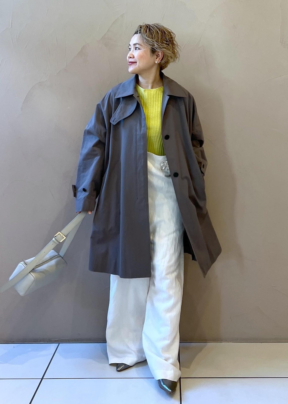 シルバー系のショルダーバッグ、イエロー系のカーディガン/ボレロ、ホワイト系のサロペット/オーバーオールを着用したレディースの冬コーディネートの4枚目の写真