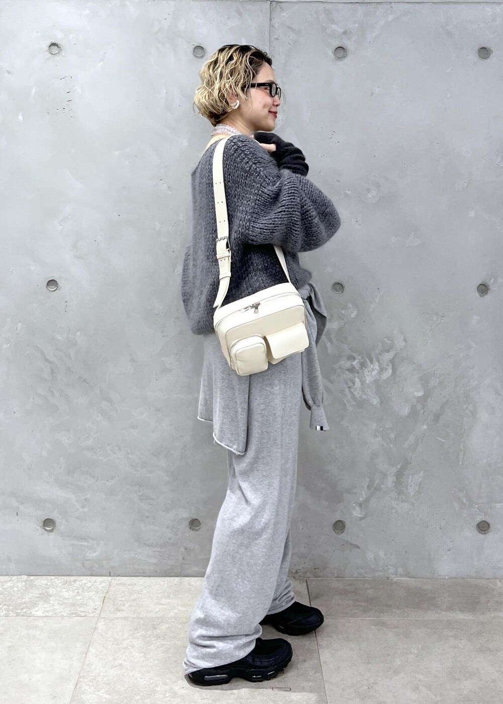 グレー系のニット/セーター、ホワイト系のボディバッグ/ウエストポーチ、グレー系の手袋を着用したレディースの秋コーディネートの3枚目の写真