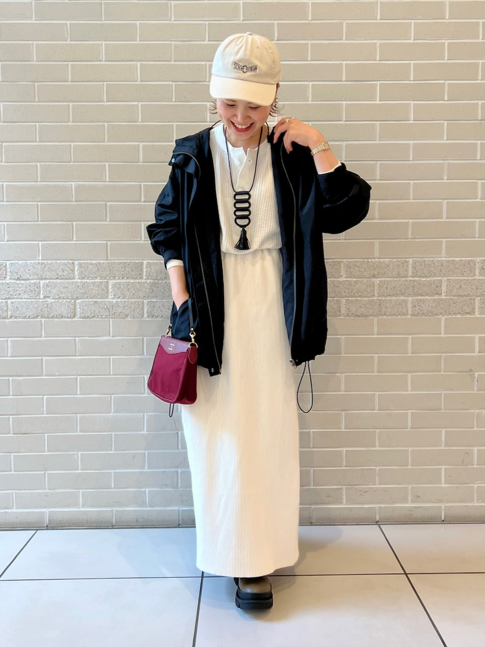 ホワイト系のTシャツ/カットソー、ブラック系のマウンテンパーカー、ホワイト系のスカートを着用したレディースの秋コーディネートの2枚目の写真