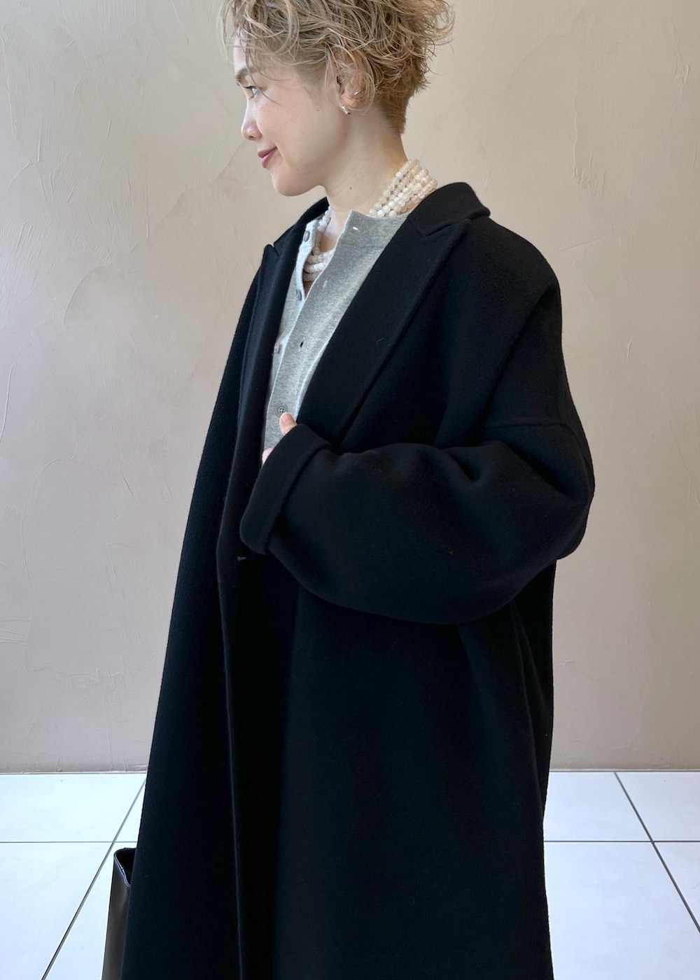 ブラック系のハンドバッグ、ブラック系のその他アウター、シルバー系のパンプスを着用したレディースの秋コーディネートの6枚目の写真