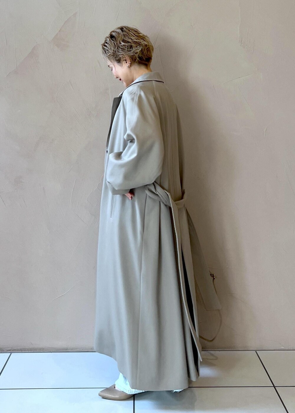 ベージュ系のボストンバッグ、ベージュ系のステンカラーコート、ブルー系のデニムパンツを着用したレディースの冬コーディネートの5枚目の写真