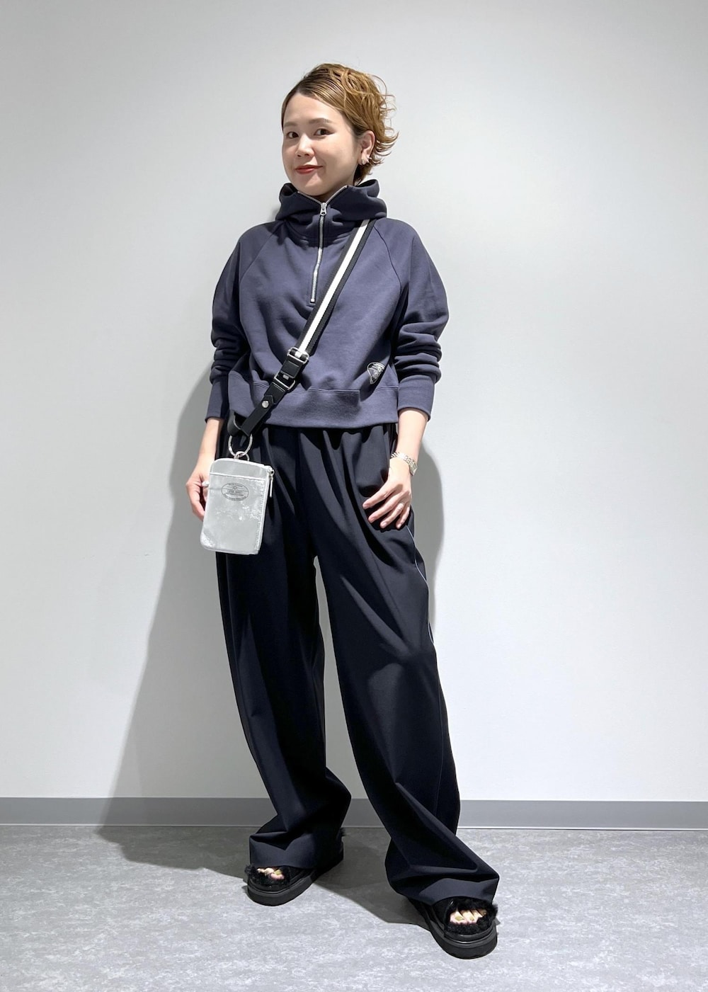 ブルー系のスラックス、グレー系のパーカー、シルバー系のトートバッグを着用したレディースの夏コーディネートの2枚目の写真