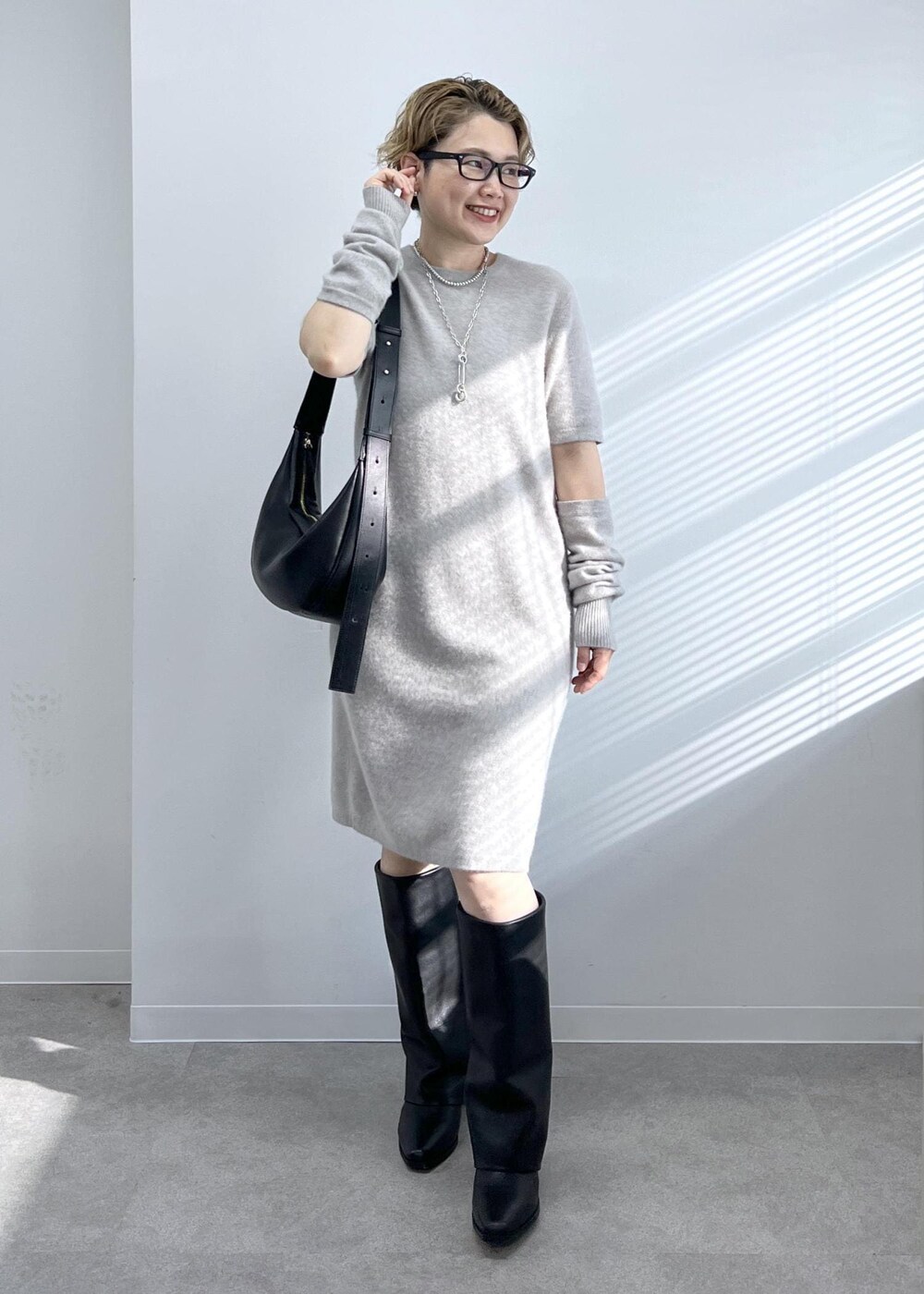 ブラック系のショルダーバッグ、ブラック系のブーツ、ベージュ系のワンピースを着用したレディースの秋コーディネートの3枚目の写真