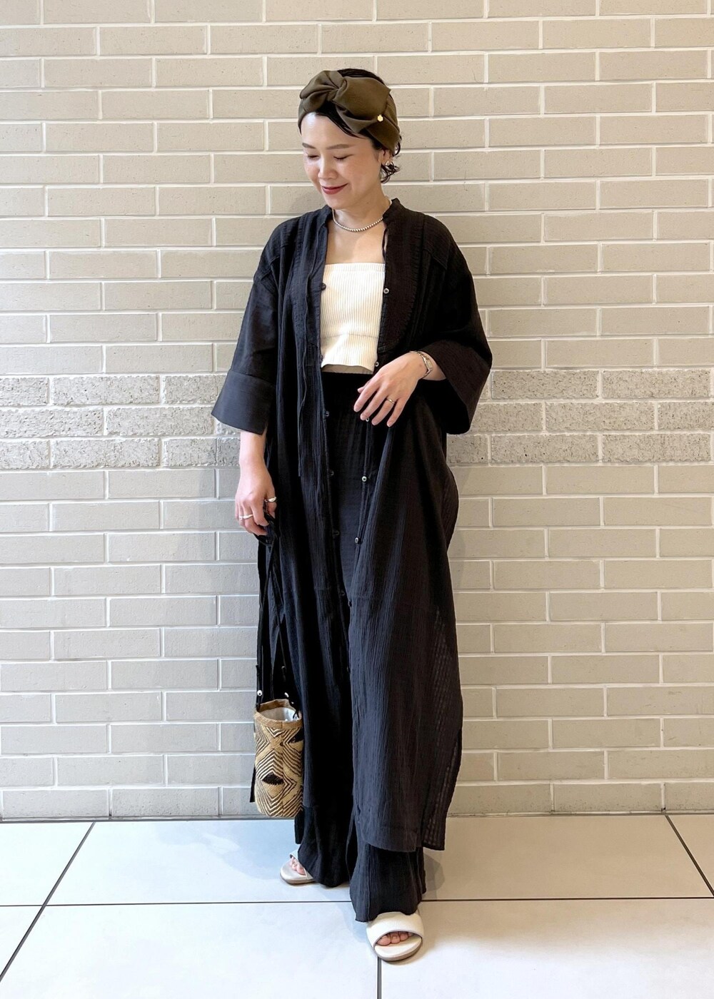 ホワイト系のチューブトップ、ベージュ系のサンダル、ブラック系のシャツ/ブラウスを着用したレディースの夏コーディネートの2枚目の写真