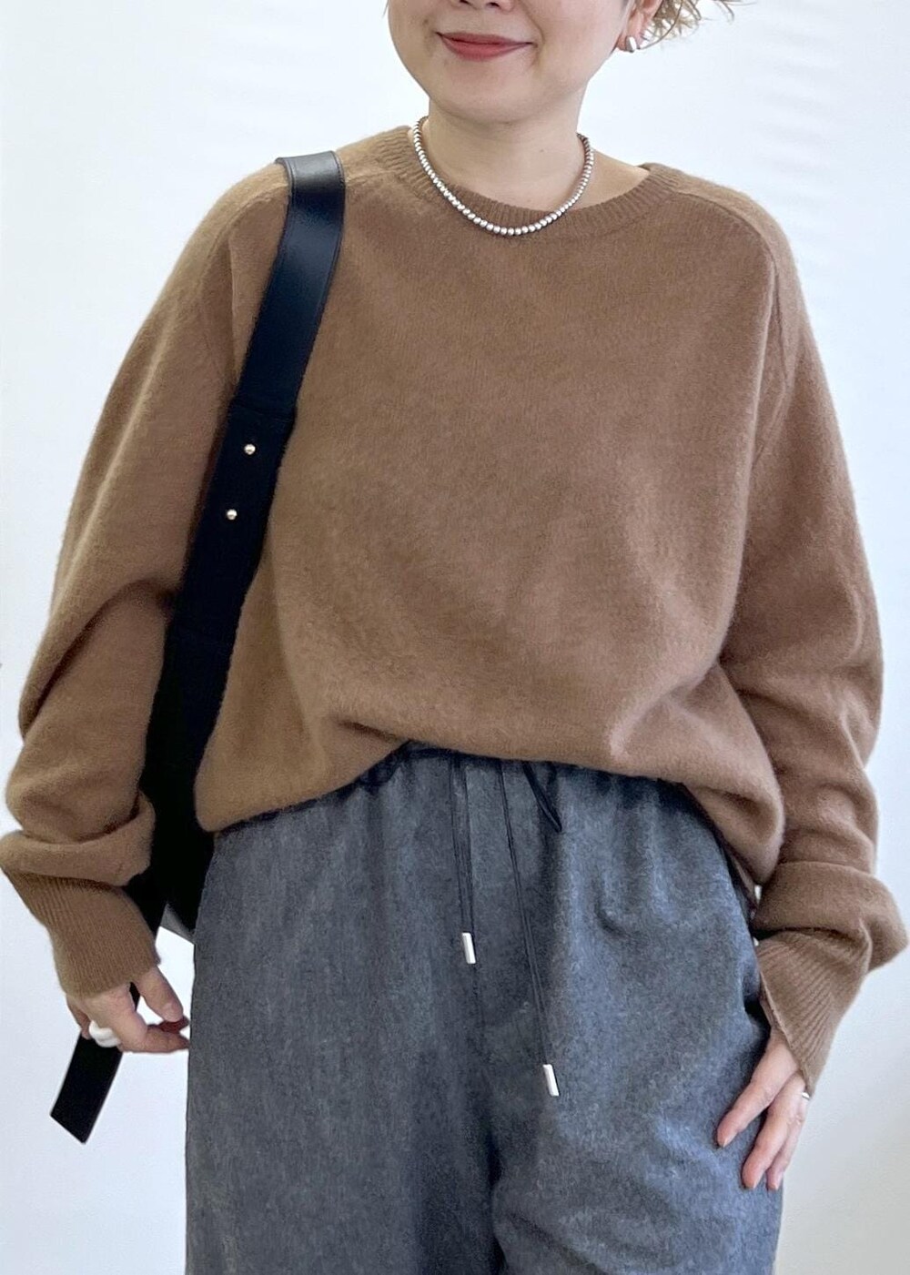 ブラック系のショルダーバッグ、グレー系のその他パンツ、ブラウン系のニット/セーターを着用したレディースの秋コーディネートの7枚目の写真