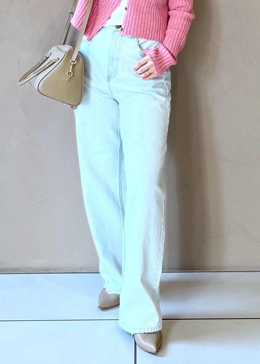 ベージュ系のボストンバッグ、ベージュ系のステンカラーコート、ブルー系のデニムパンツを着用したレディースの冬コーディネートの10枚目の写真