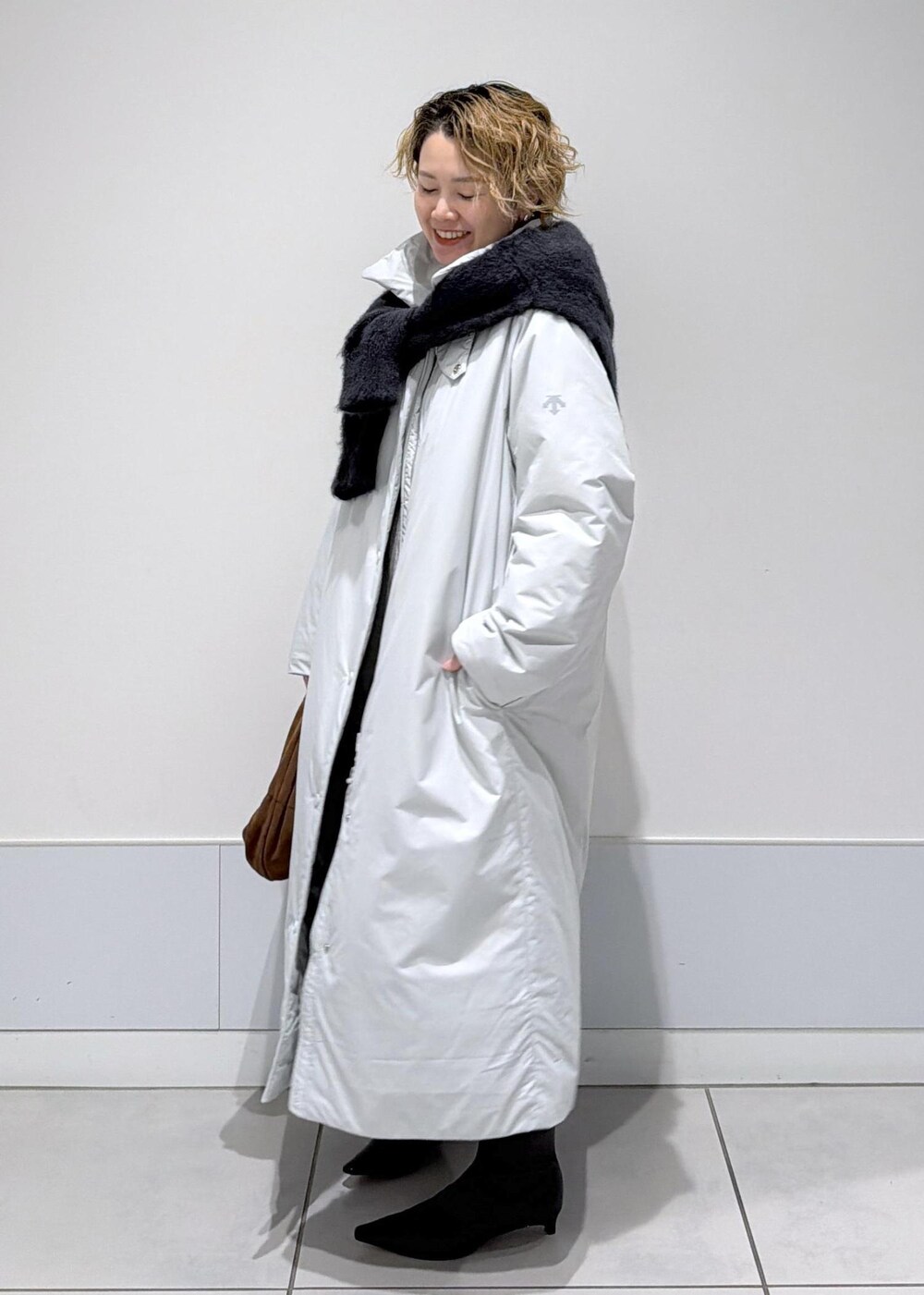 ブラック系のスカート、ブラウン系のハンドバッグ、グレー系のダウンジャケット/コートを着用したレディースの秋コーディネートの4枚目の写真