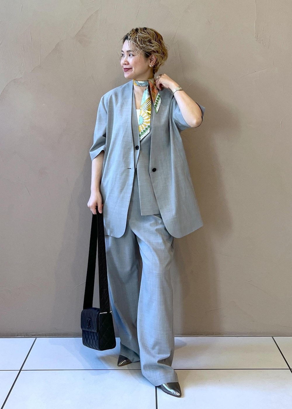 グレー系のベスト、グレー系のスラックス、グレー系のテーラードジャケットを着用したレディースの冬コーディネートの2枚目の写真