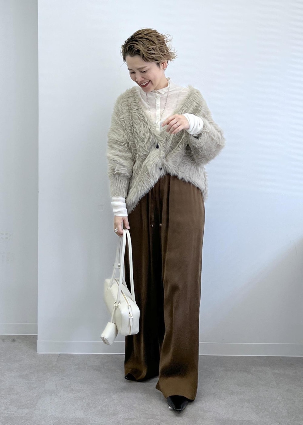 ベージュ系のカーディガン/ボレロ、ブラウン系のその他パンツ、ホワイト系のショルダーバッグを着用したレディースの秋コーディネートの4枚目の写真