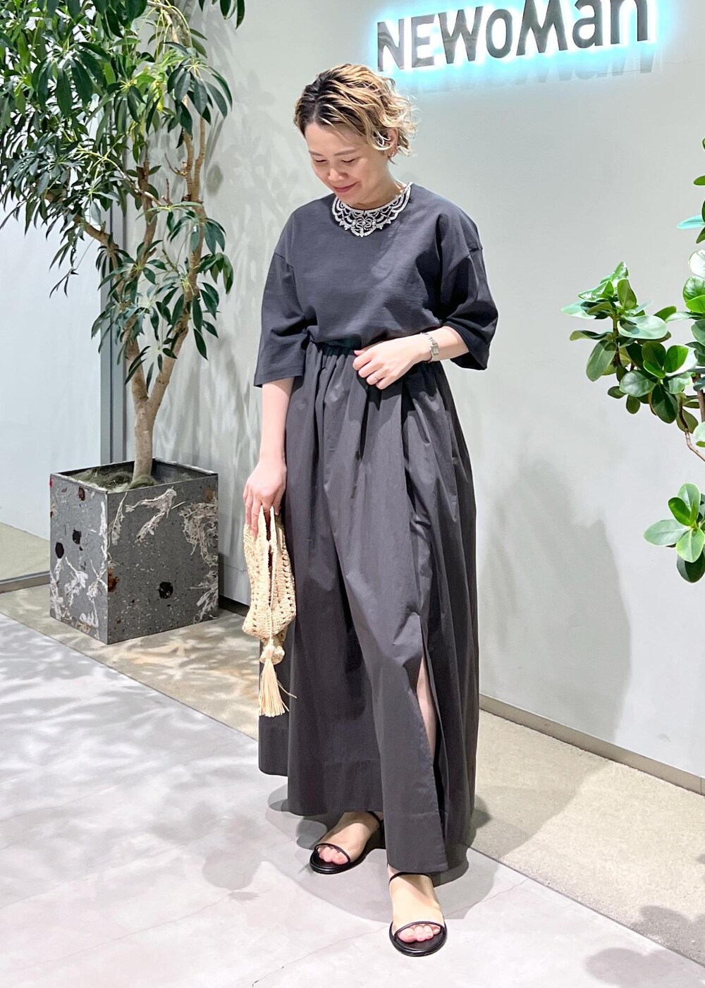 グレー系のスカート、グレー系のTシャツ/カットソー、ホワイト系のサンダルを着用したレディースの春コーディネートの2枚目の写真