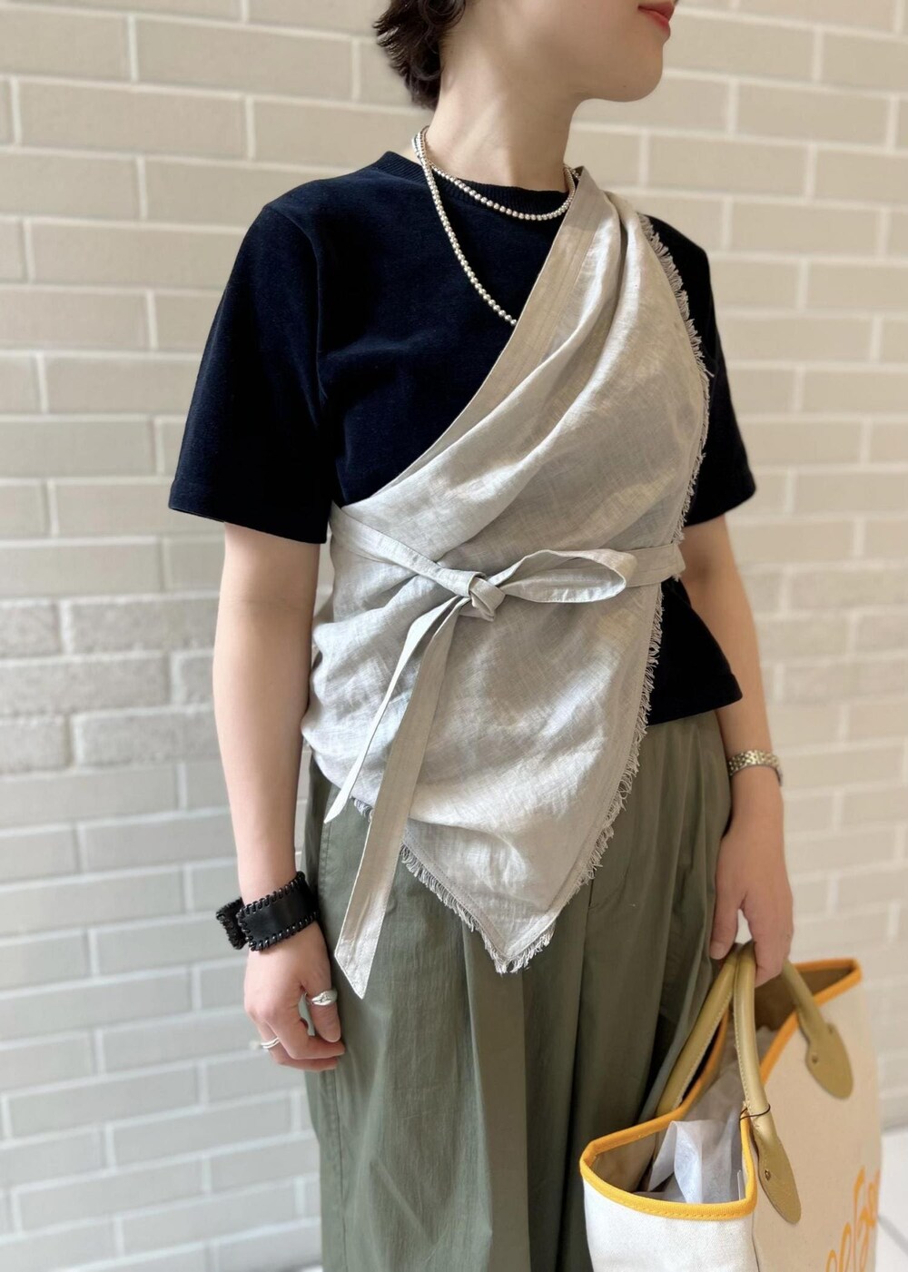 ホワイト系のトートバッグ、ブラック系のTシャツ/カットソー、グリーン系のその他パンツを着用したレディースの春コーディネートの4枚目の写真