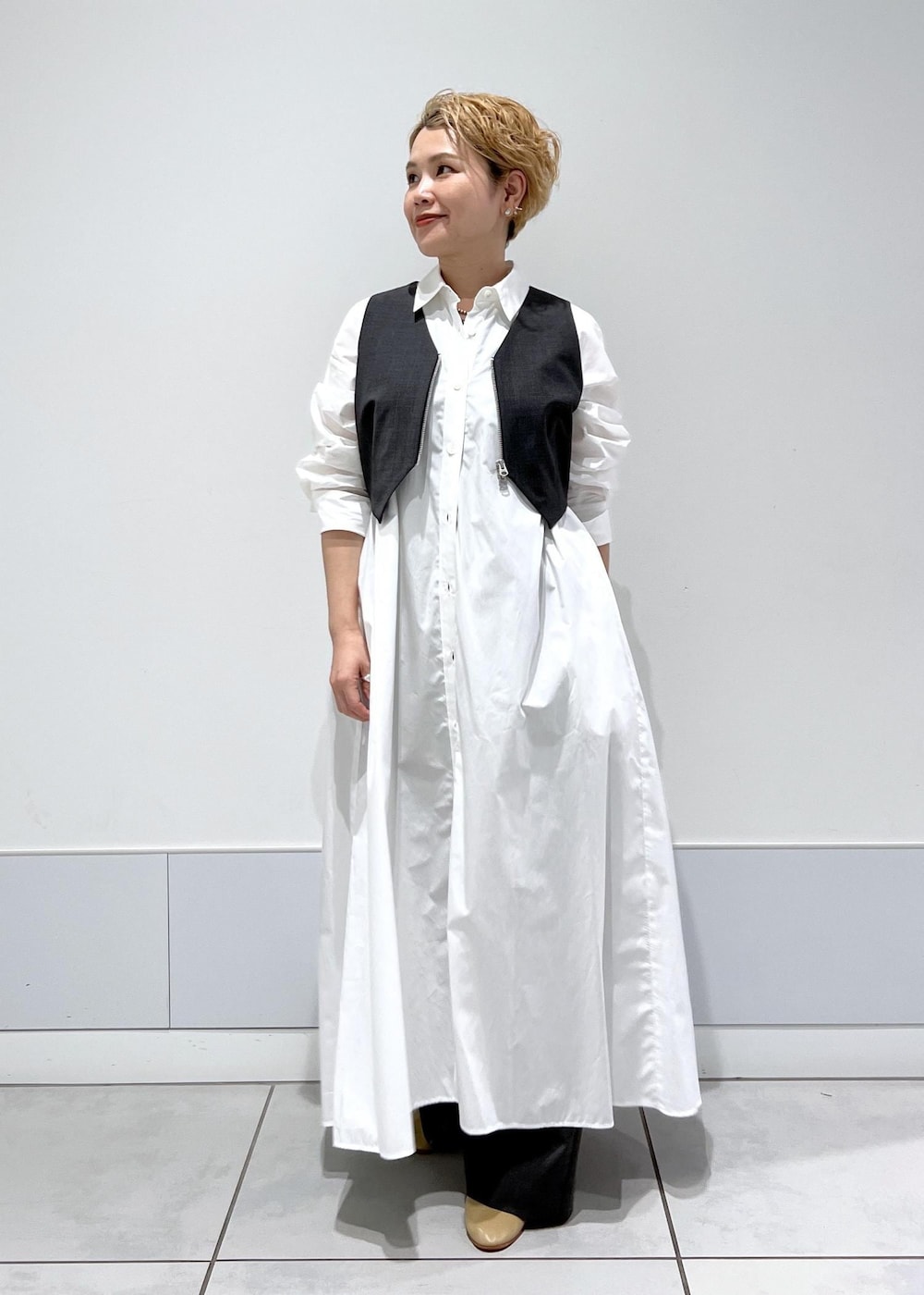 ホワイト系のシャツワンピース、ブラック系のタンクトップ、グレー系のベストを着用したレディースの秋コーディネートの3枚目の写真