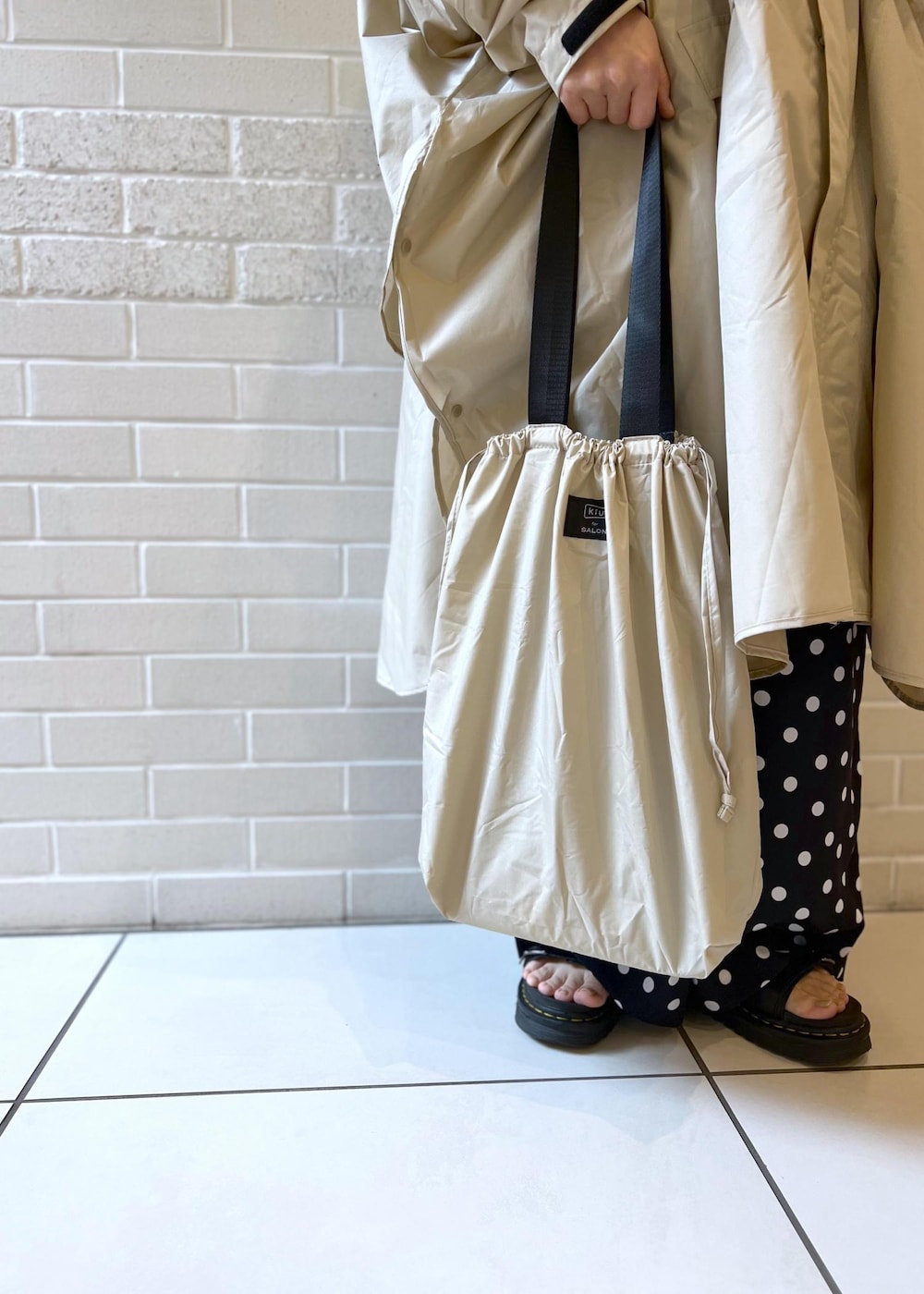 ベージュ系のトートバッグ、ブラック系のつなぎ/オールインワン、ベージュ系のレインコート/ポンチョを着用したレディースの夏コーディネートの8枚目の写真