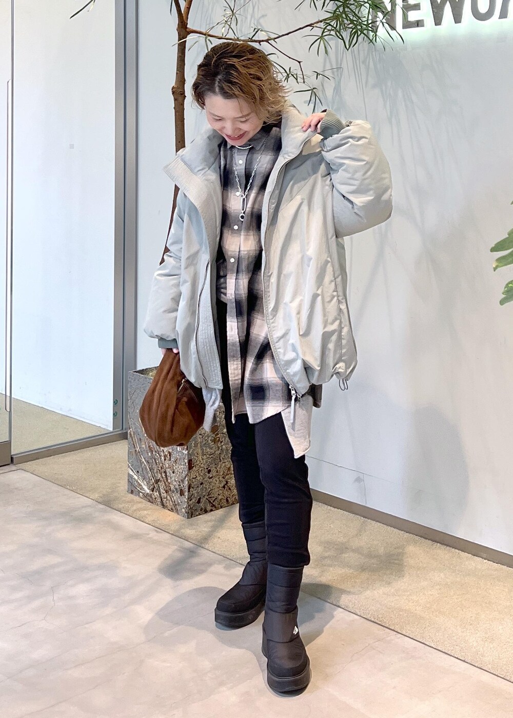 グリーン系のダウンジャケット/コート、ブラウン系のハンドバッグ、ブラック系のブーツを着用したレディースの秋コーディネートの4枚目の写真