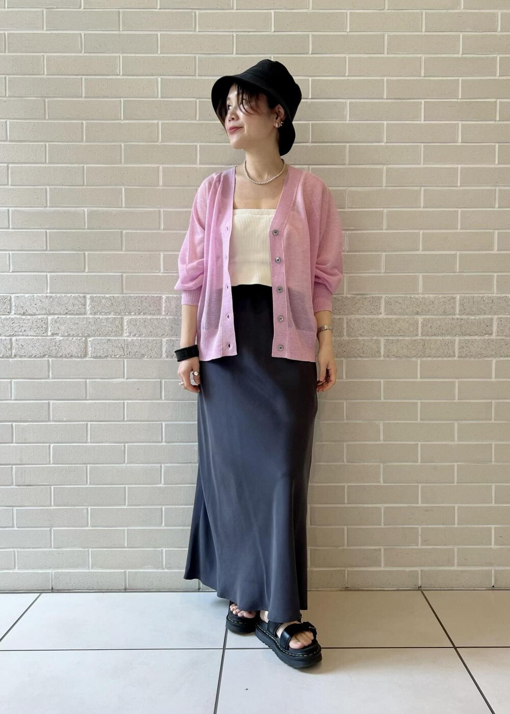 グレー系のスカート、ピンク系のカーディガン/ボレロ、ホワイト系のチューブトップを着用したレディースの春コーディネートの4枚目の写真