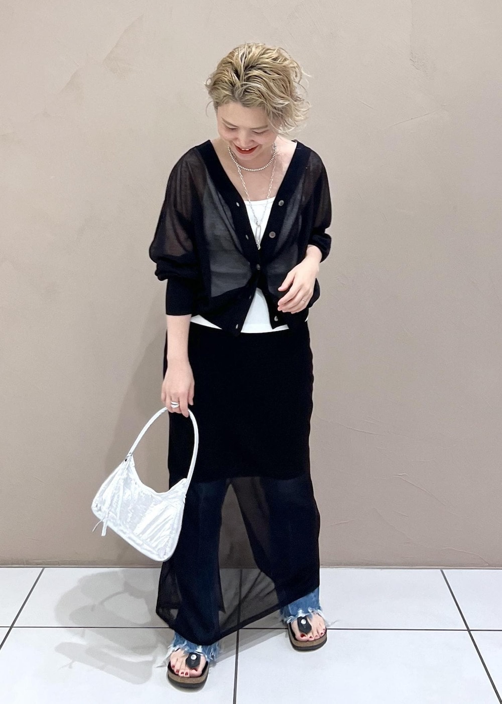 ホワイト系のタンクトップ、ブラック系のカーディガン/ボレロ、ブルー系のデニムパンツを着用したレディースの夏コーディネートの4枚目の写真