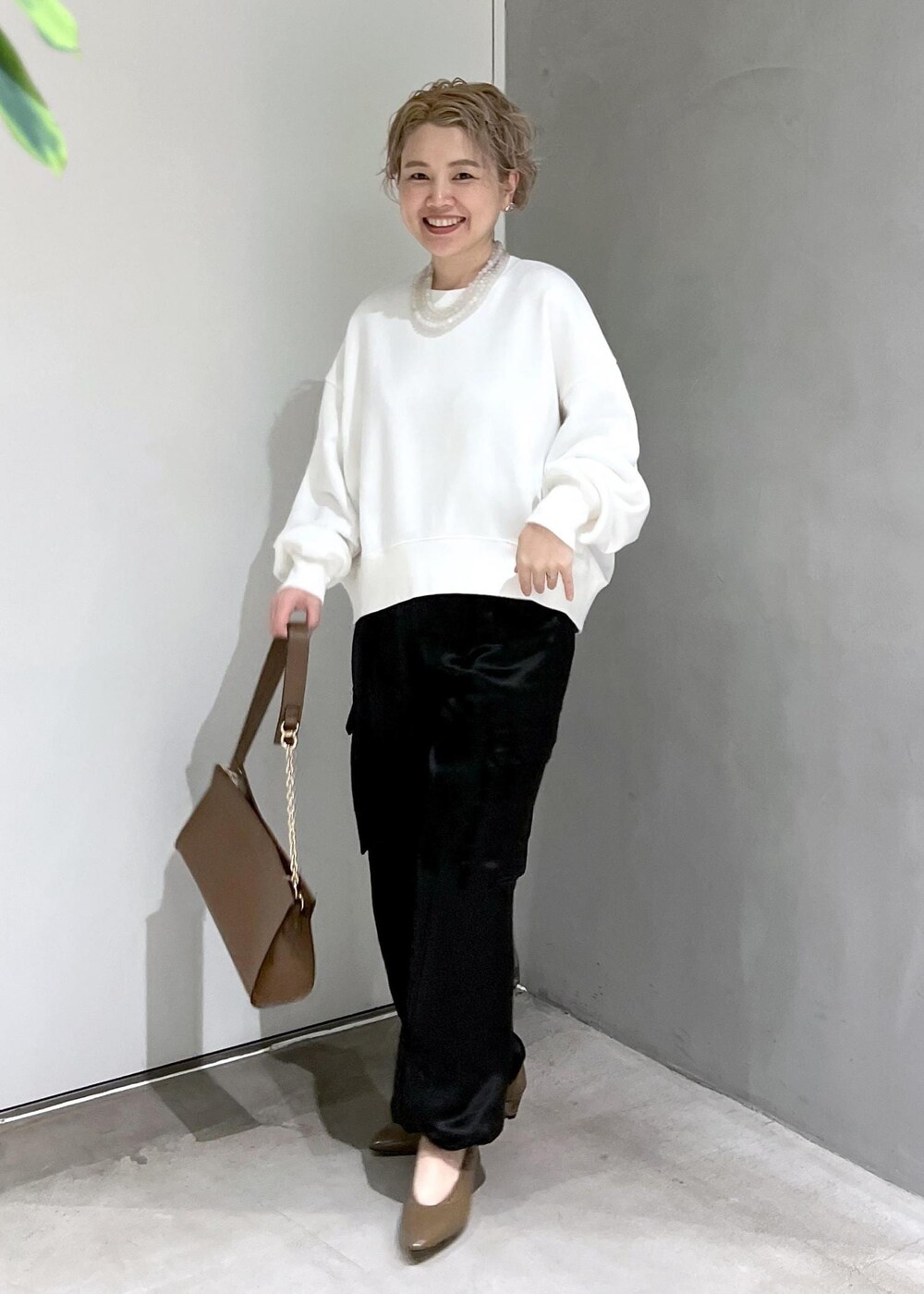 ホワイト系のスウェット、ブラック系のカーゴパンツ、ブラウン系のショルダーバッグを着用したレディースの秋コーディネートの4枚目の写真