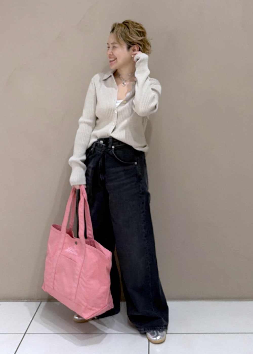 ベージュ系のカーディガン/ボレロ、ピンク系のトートバッグ、ブラック系のデニムパンツを着用したレディースの冬コーディネートの4枚目の写真