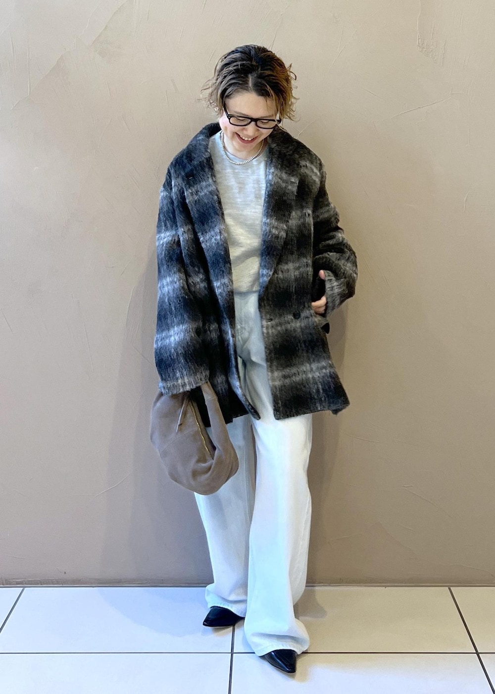 ブルー系のデニムパンツ、グレー系のその他アウター、グレー系のハンドバッグを着用したレディースの秋コーディネートの3枚目の写真