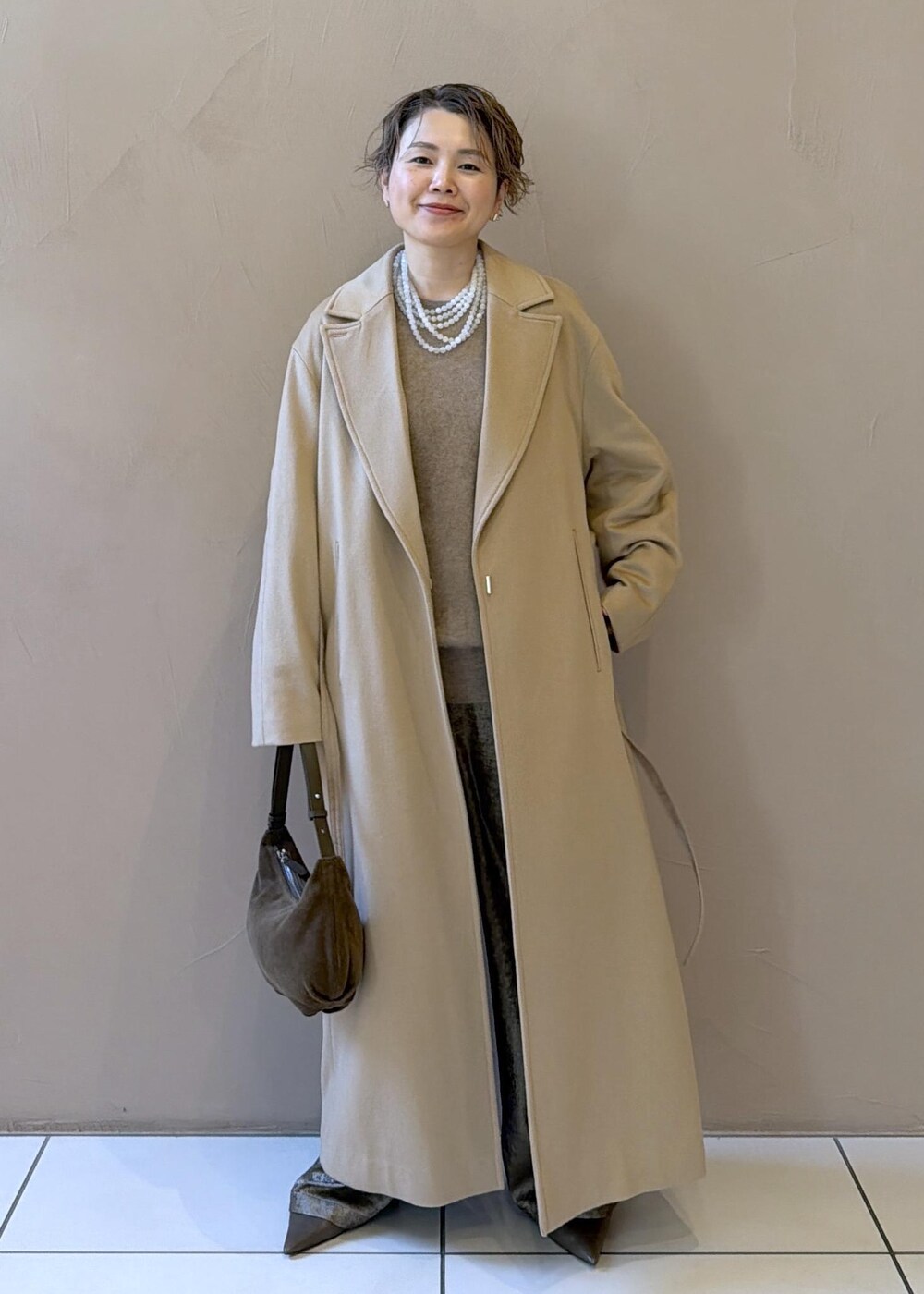 イエロー系のトレンチコート、ゴールド系のその他パンツ、ベージュ系のニット/セーターを着用したレディースの冬コーディネートの4枚目の写真