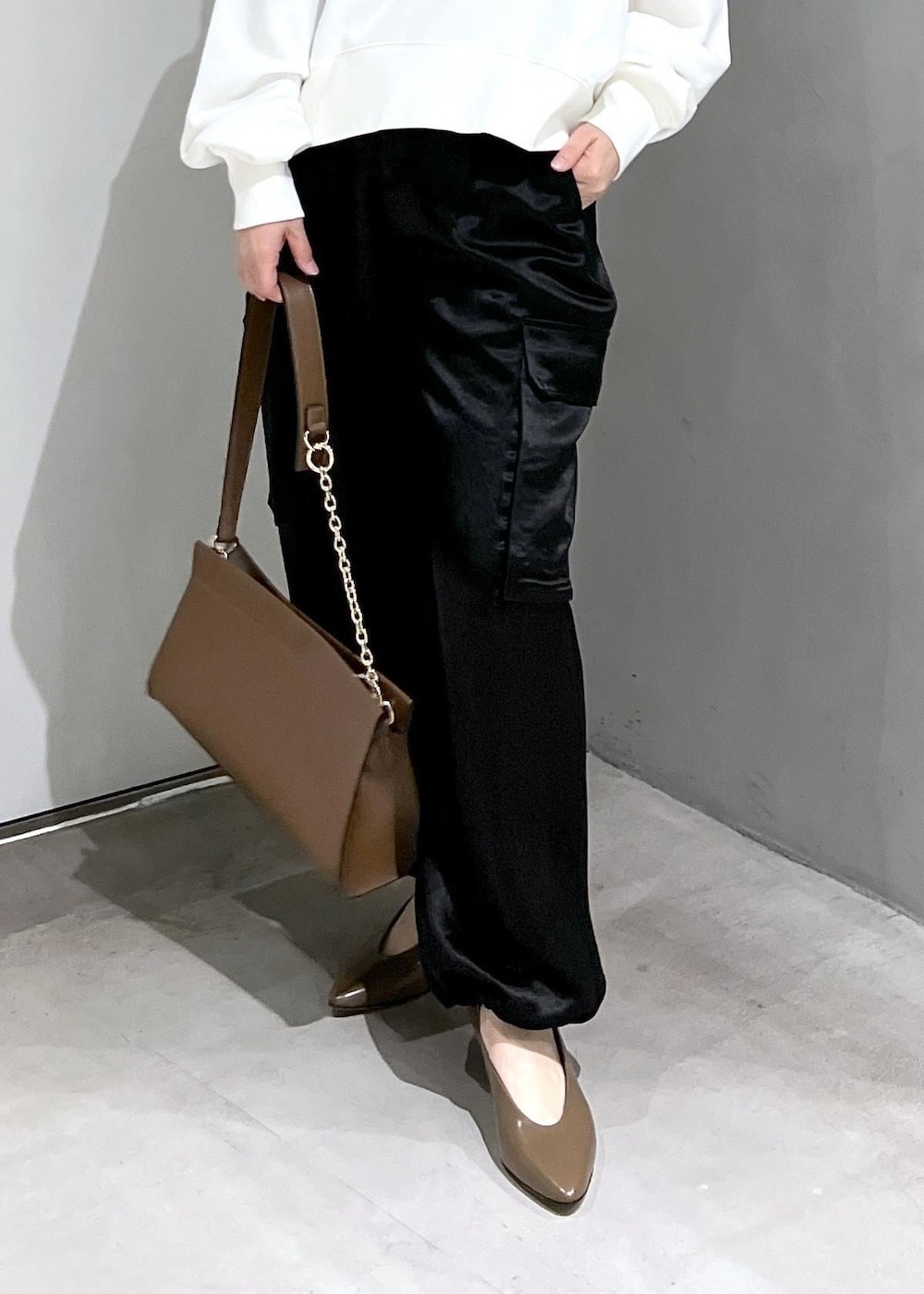 ホワイト系のスウェット、ブラック系のカーゴパンツ、ブラウン系のショルダーバッグを着用したレディースの秋コーディネートの9枚目の写真