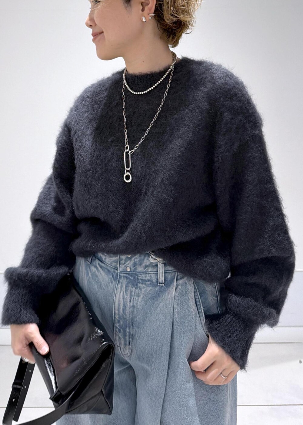 ブラック系のショルダーバッグ、ブラック系のブーツ、ブルー系のデニムパンツを着用したレディースの秋コーディネートの6枚目の写真