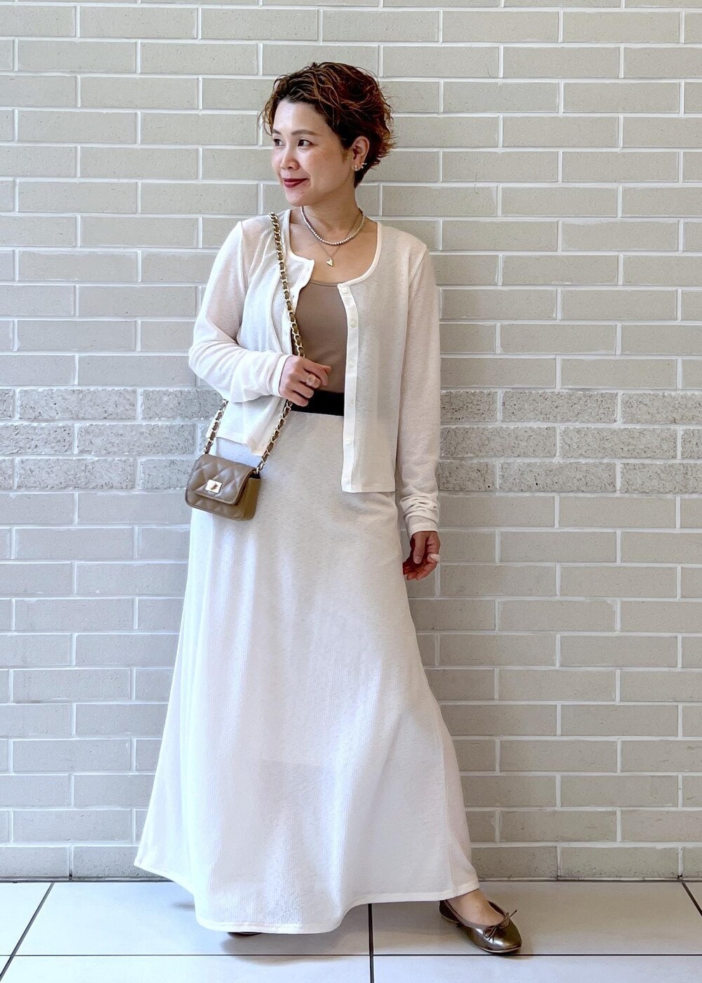 ホワイト系のスカート、ベージュ系のショルダーバッグ、ホワイト系のカーディガン/ボレロを着用したレディースの夏コーディネートの4枚目の写真