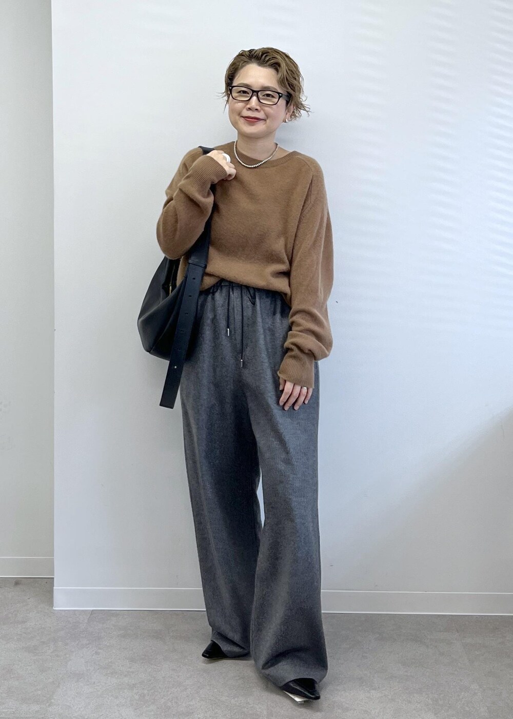 ブラック系のショルダーバッグ、グレー系のその他パンツ、ブラウン系のニット/セーターを着用したレディースの秋コーディネートの2枚目の写真