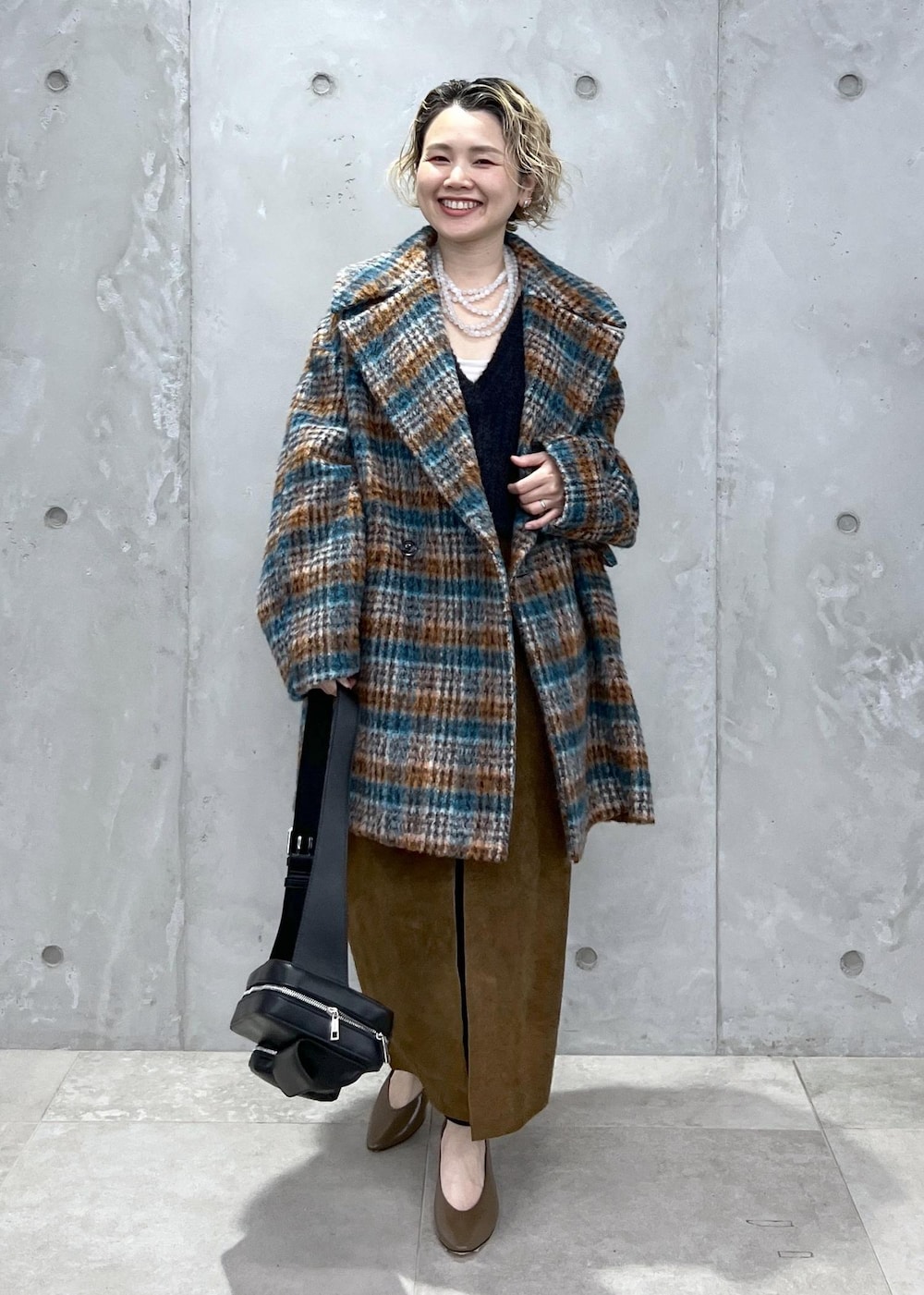 ブラック系のベスト、ブルー系のピーコート、ブラック系のボディバッグ/ウエストポーチを着用したレディースの秋コーディネートの2枚目の写真