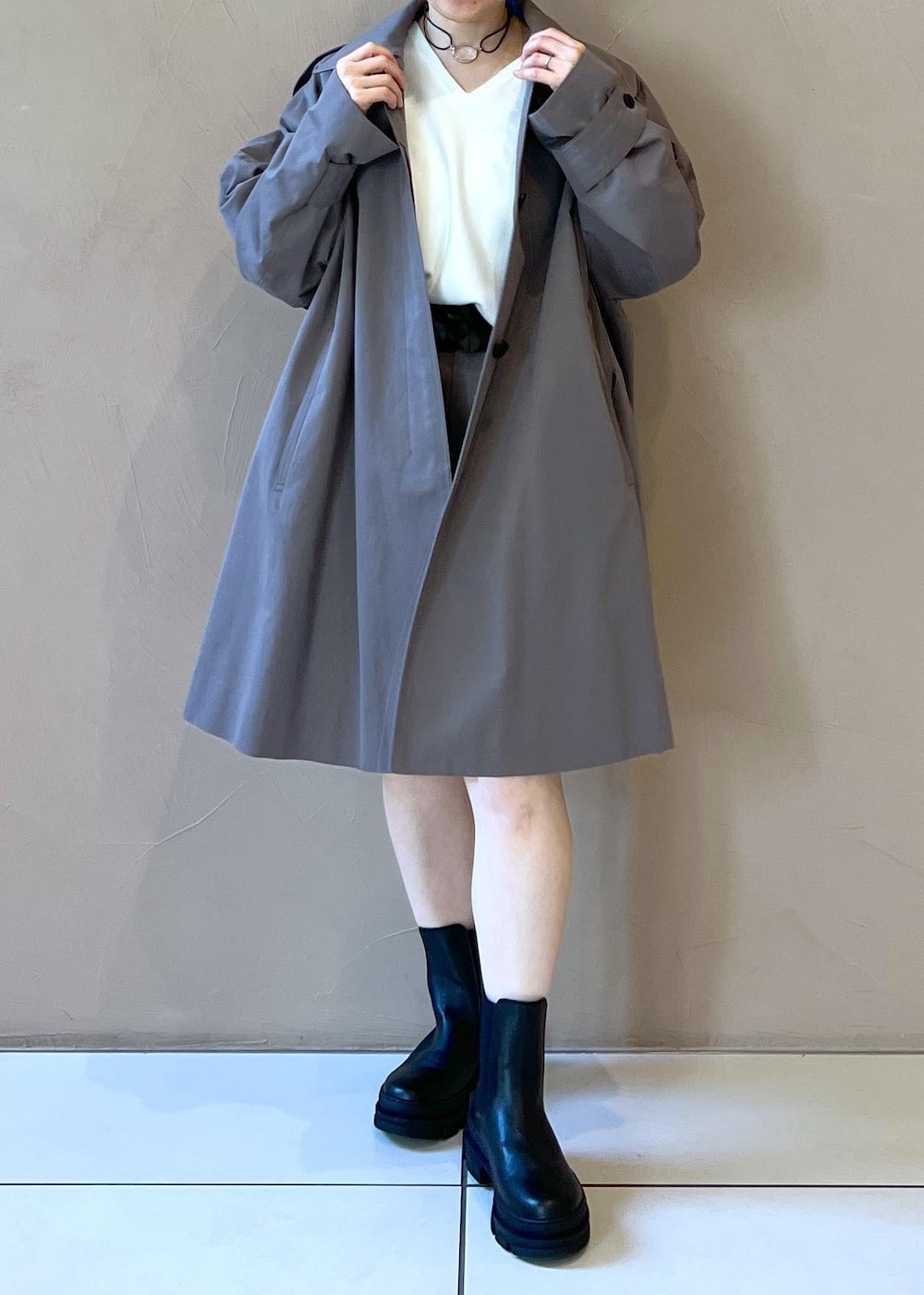 ブラック系のブーツ、ホワイト系のニット/セーター、グレー系のステンカラーコートを着用したレディースの冬コーディネートの7枚目の写真