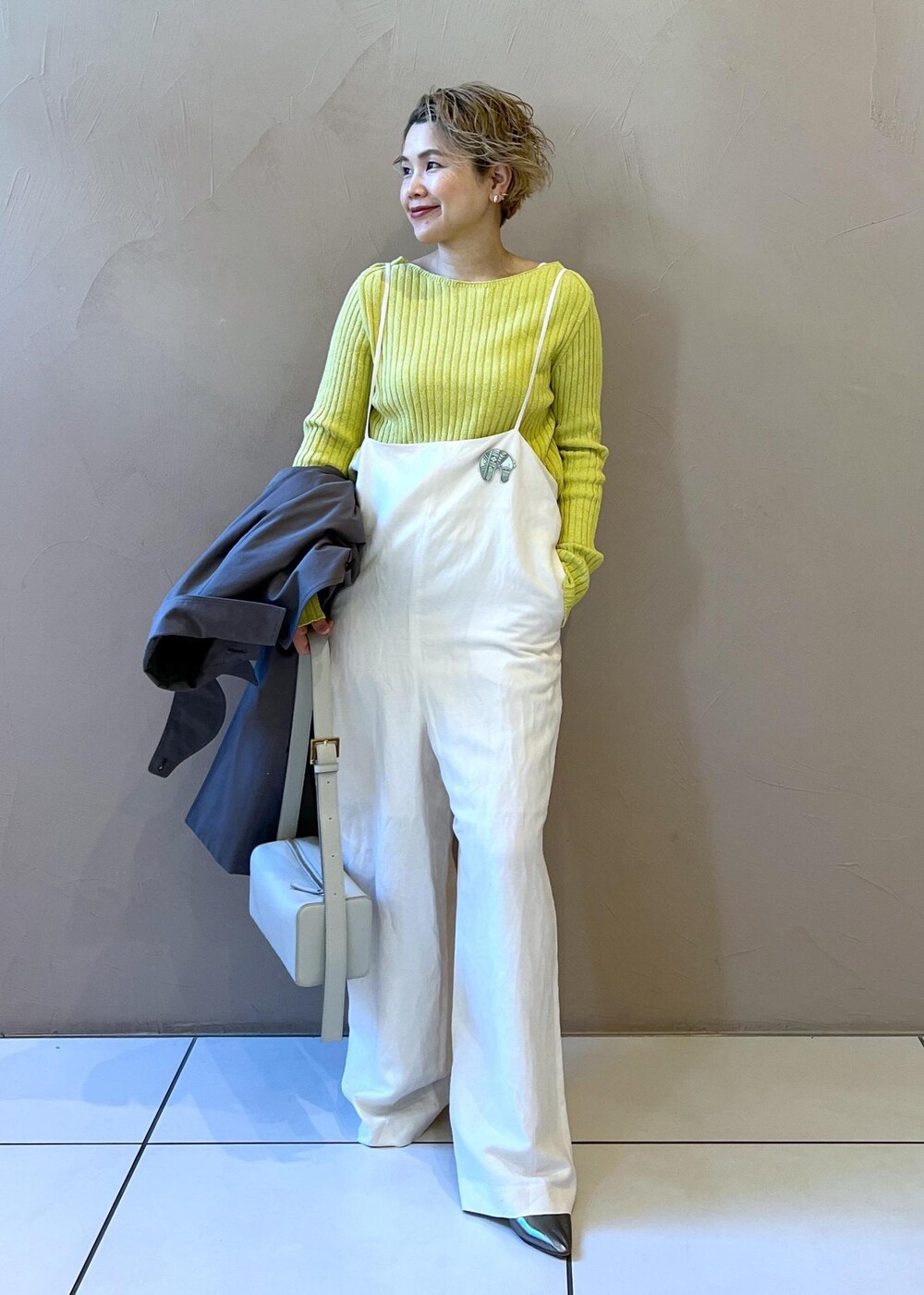 シルバー系のショルダーバッグ、イエロー系のカーディガン/ボレロ、ホワイト系のサロペット/オーバーオールを着用したレディースの冬コーディネートの9枚目の写真