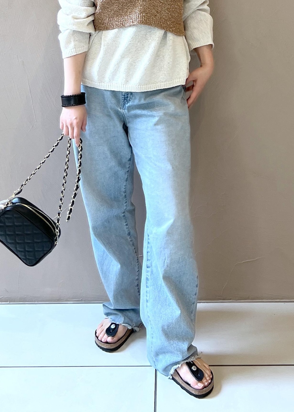 ブラック系のショルダーバッグ、ブルー系のデニムパンツ、ホワイト系のニット/セーターを着用したレディースの春コーディネートの5枚目の写真