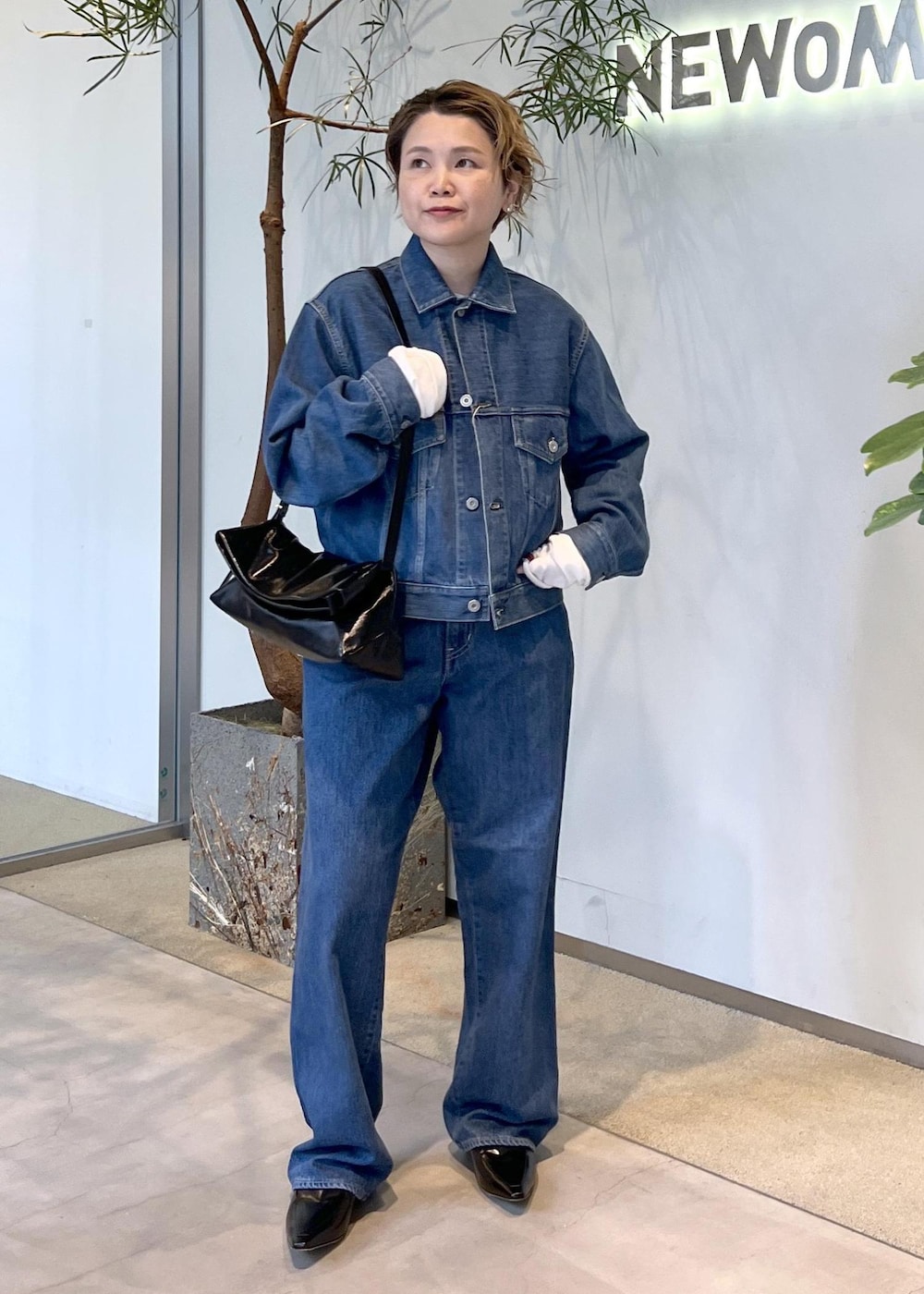 ブラック系のショルダーバッグ、ブルー系のデニムジャケット、ブルー系のデニムパンツを着用したレディースの秋コーディネートの4枚目の写真