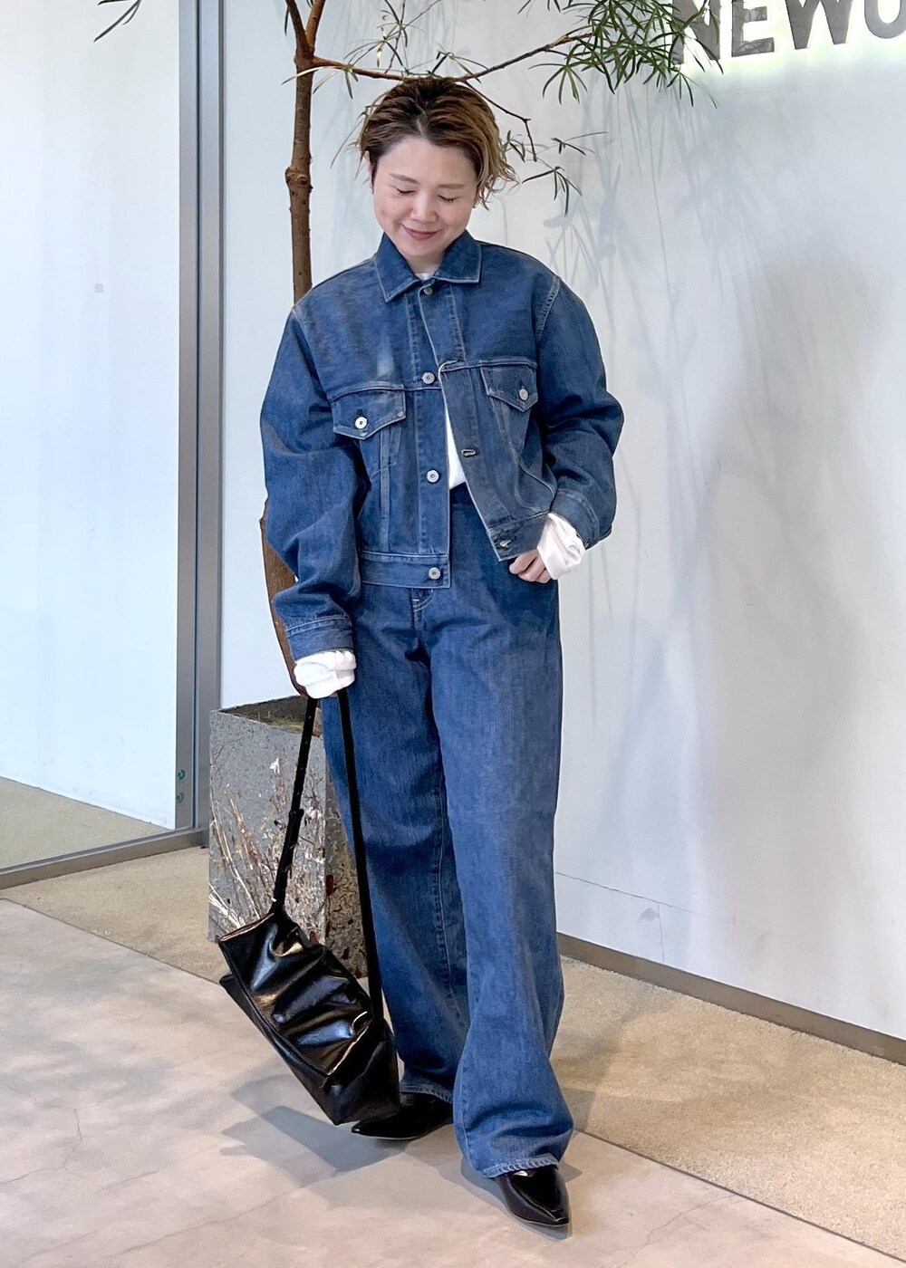 ブラック系のショルダーバッグ、ブルー系のデニムジャケット、ブルー系のデニムパンツを着用したレディースの秋コーディネートの2枚目の写真