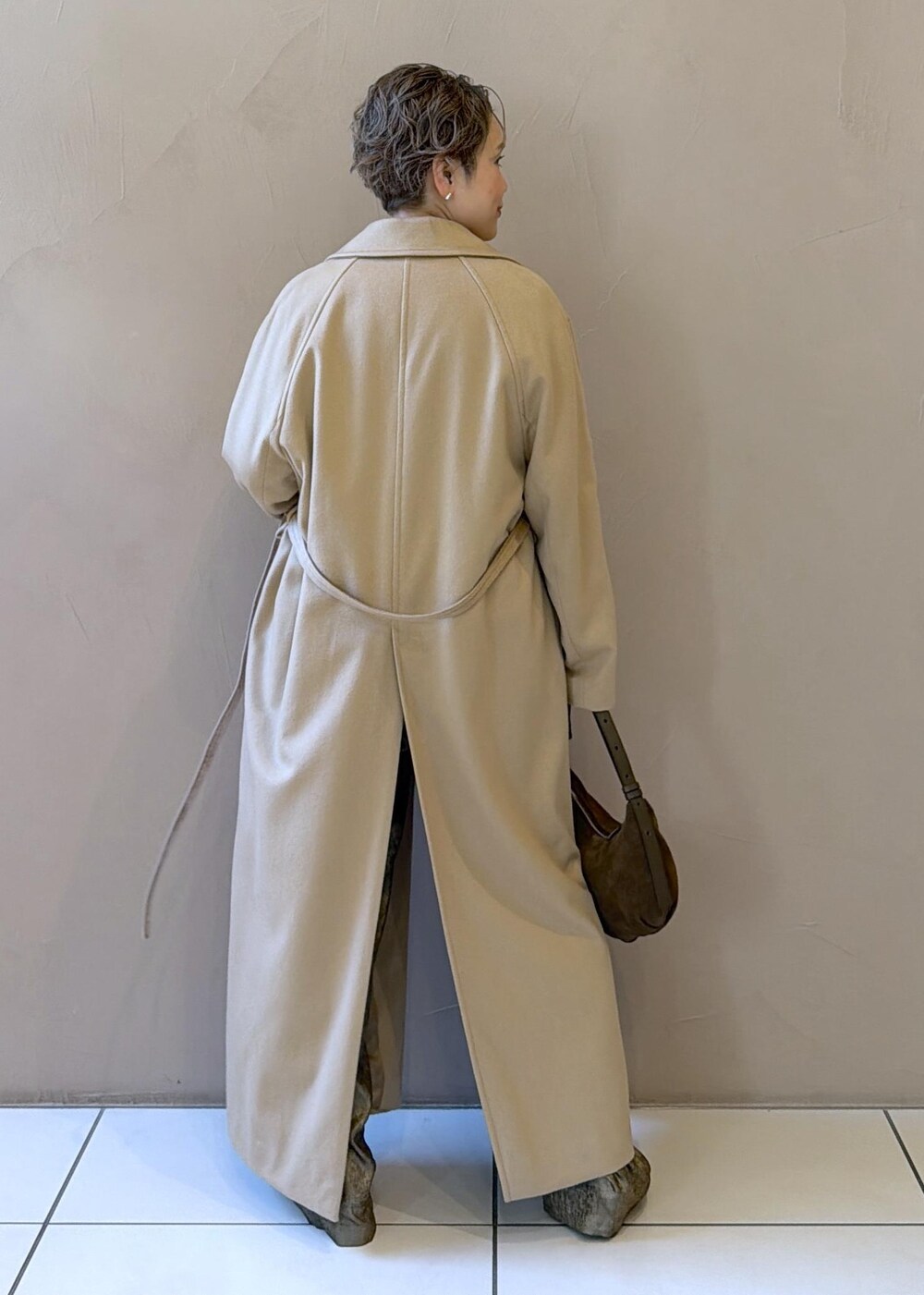 イエロー系のトレンチコート、ゴールド系のその他パンツ、ベージュ系のニット/セーターを着用したレディースの冬コーディネートの6枚目の写真