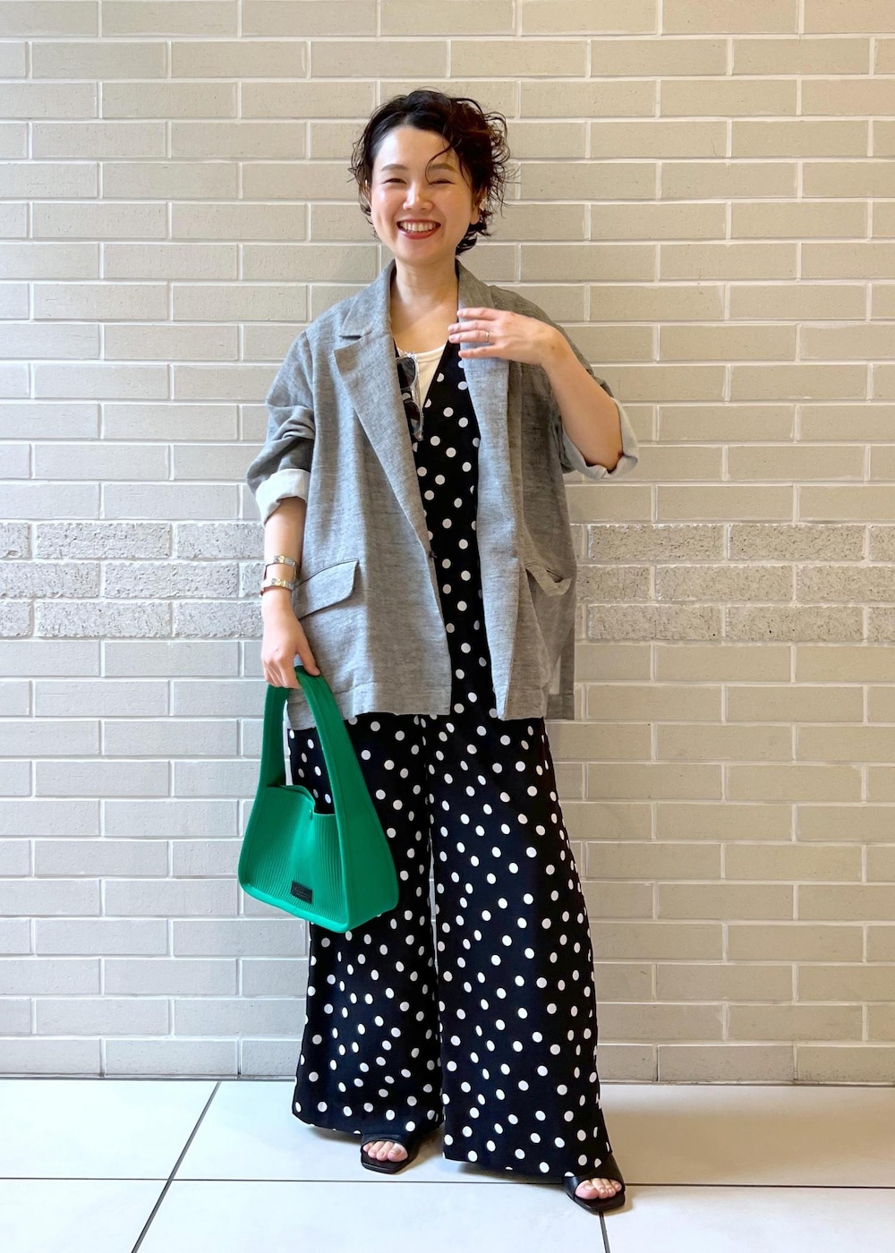 ホワイト系のタンクトップ、グリーン系のハンドバッグ、ブラック系のサンダルを着用したレディースの夏コーディネートの2枚目の写真