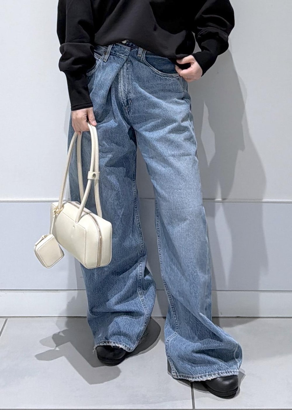 ブラック系のスウェット、ブルー系のデニムパンツを着用したレディースの冬コーディネートの6枚目の写真