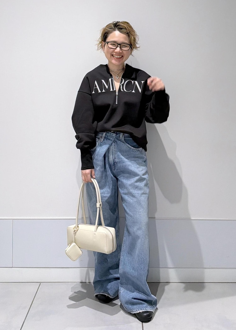 ブラック系のスウェット、ブルー系のデニムパンツを着用したレディースの冬コーディネートの2枚目の写真