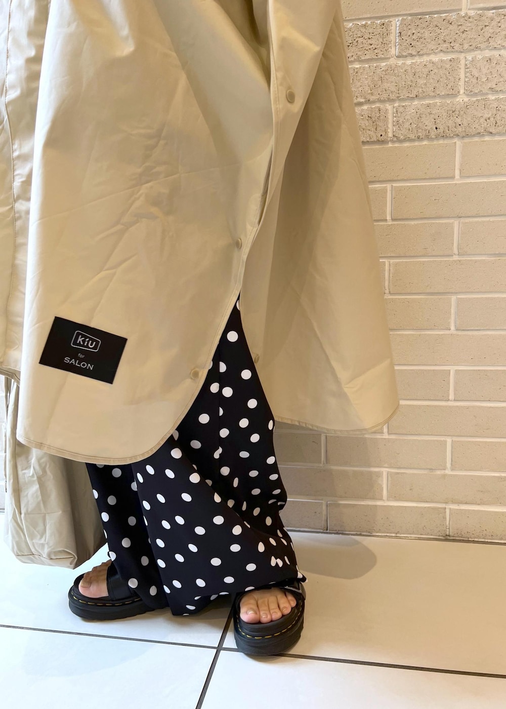 ベージュ系のトートバッグ、ブラック系のつなぎ/オールインワン、ベージュ系のレインコート/ポンチョを着用したレディースの夏コーディネートの6枚目の写真