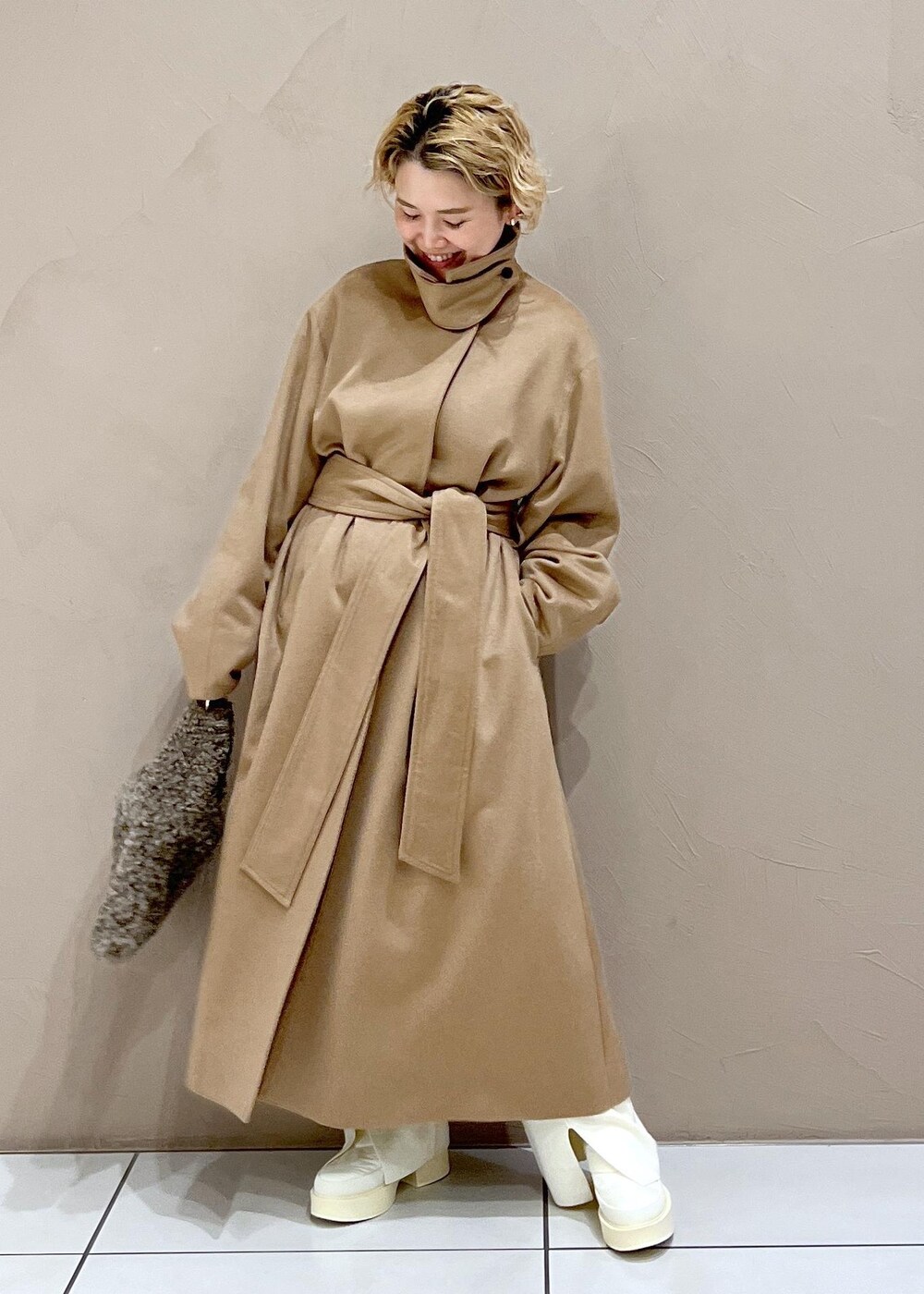 ブラウン系のハンドバッグ、ホワイト系のTシャツ/カットソー、イエロー系のステンカラーコートを着用したレディースの冬コーディネートの3枚目の写真