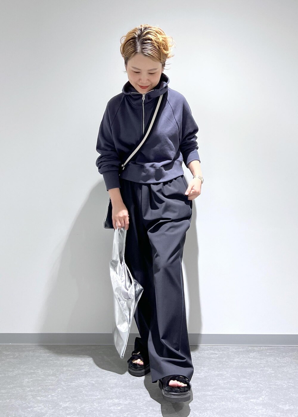 ブルー系のスラックス、グレー系のパーカー、シルバー系のトートバッグを着用したレディースの夏コーディネートの3枚目の写真