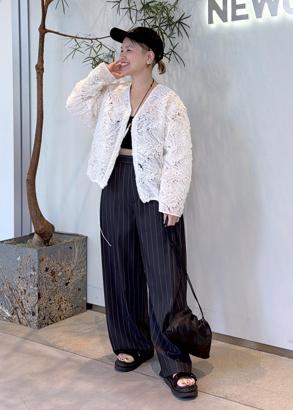 グレー系のその他パンツ、ブラック系のショルダーバッグ、ホワイト系のシャツ/ブラウスを着用したレディースの夏コーディネートの4枚目の写真