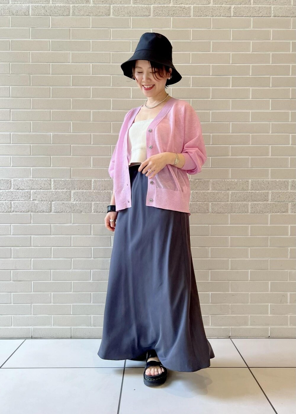 グレー系のスカート、ピンク系のカーディガン/ボレロ、ホワイト系のチューブトップを着用したレディースの春コーディネートの3枚目の写真