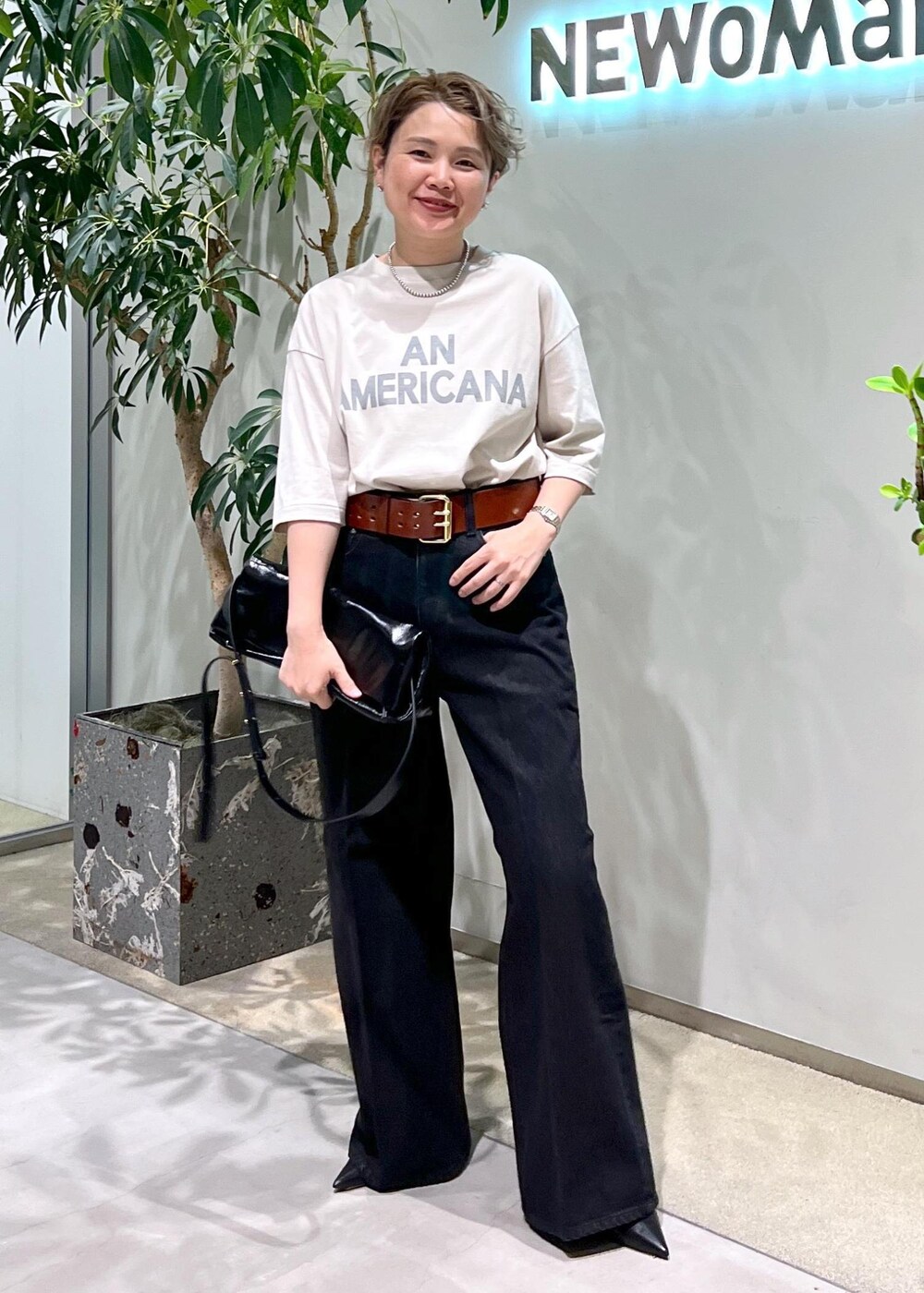 グレー系のデニムパンツ、ブラック系のショルダーバッグ、ホワイト系のTシャツ/カットソーを着用したレディースの夏コーディネートの2枚目の写真